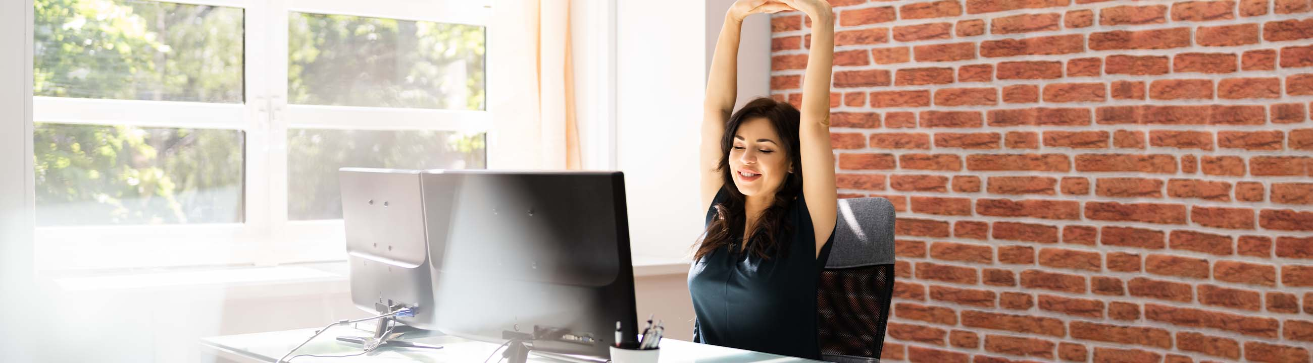 Mulher sentada no escritório a alongar os braços